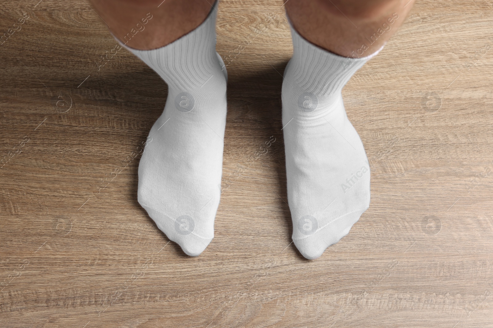 Photo of Man in stylish white socks standing on wooden floor, top view