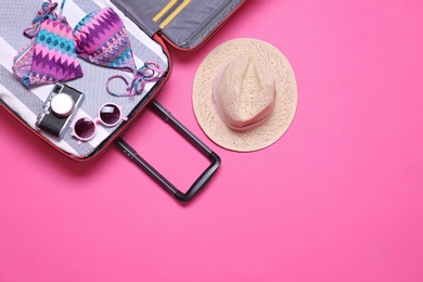 Photo of Open suitcase and beach objects on pink background, flat lay. Space for text