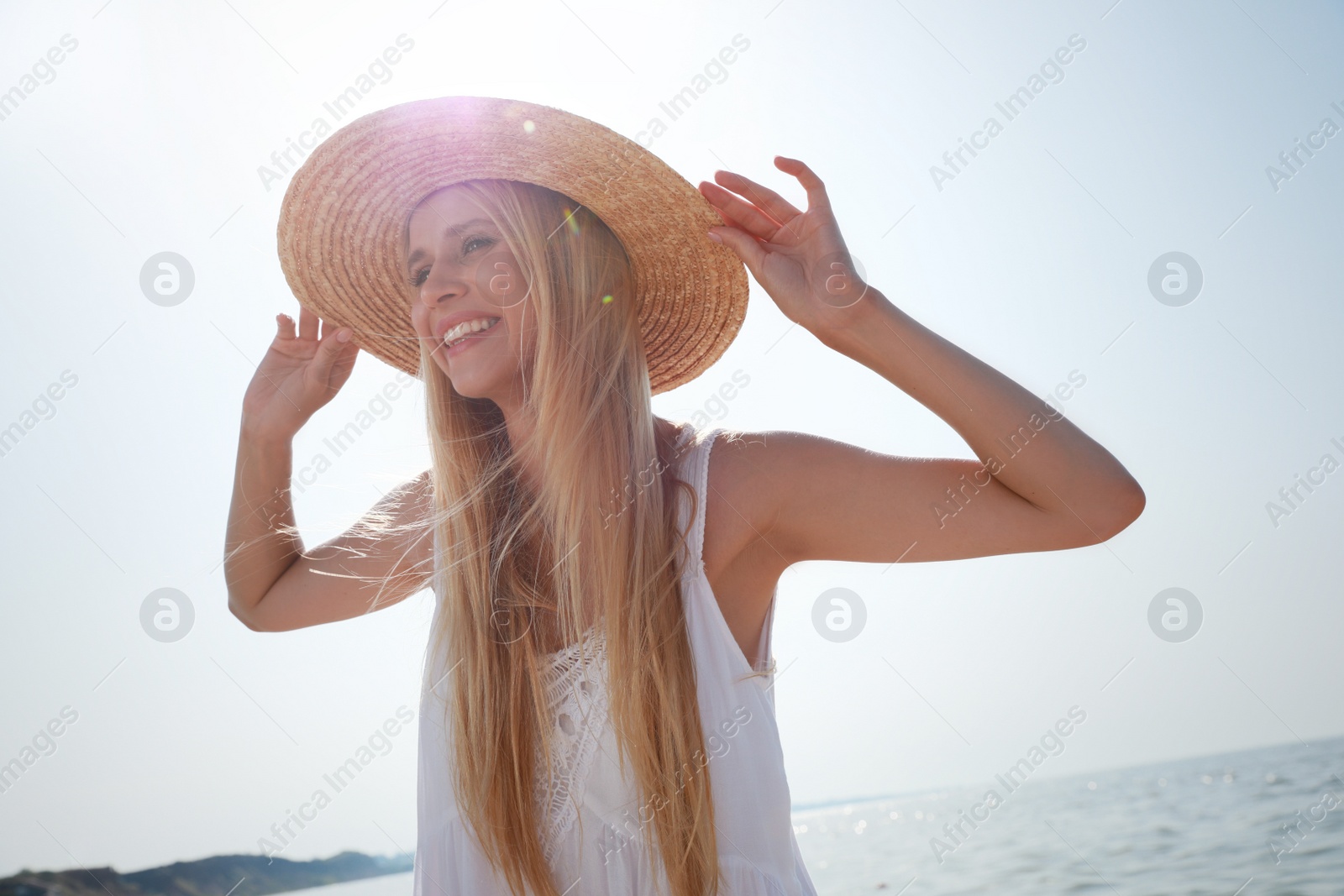 Photo of Beautiful young woman with straw hat near sea on sunny day in summer