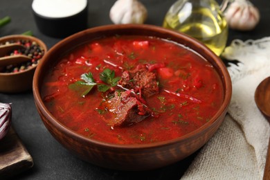 Photo of Stylish brown clay bowl with Ukrainian borsch served on black table