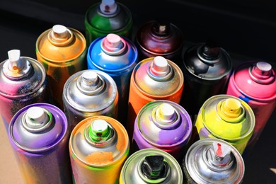 Photo of Many different used cans of spray paint, above view. Graffiti supplies
