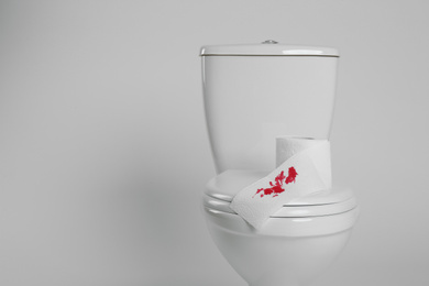 Paper with blood stain on toilet bowl against white background. Hemorrhoids concept