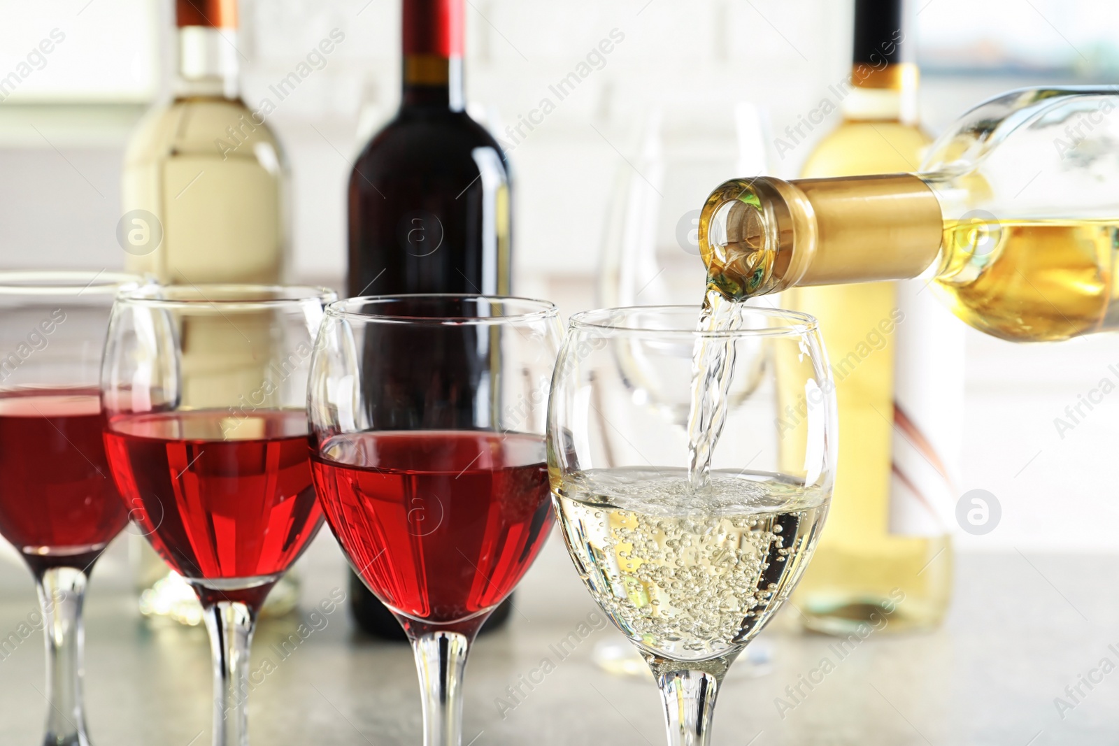 Photo of Pouring delicious white wine into glass on table