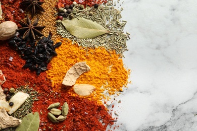 Photo of Different aromatic spices on marble background, top view with space for text