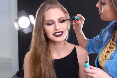Professional makeup artist working with beautiful young woman in photo studio