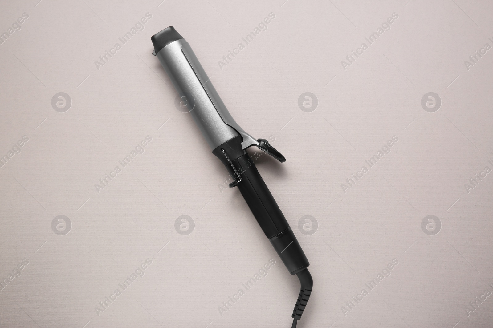 Photo of Hair curling iron on grey background, top view