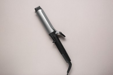 Hair curling iron on grey background, top view