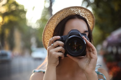 Photo of Young photographer taking picture with professional camera outdoors