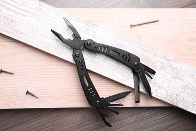 Photo of Modern compact portable multitool, nails and planks on wooden table, flat lay