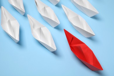 Paper boats following red one on light blue background. Leadership concept