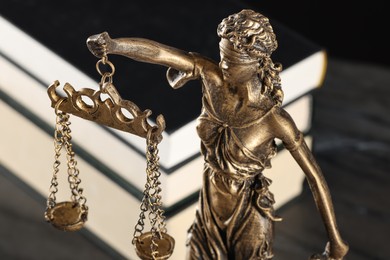 Symbol of fair treatment under law. Figure of Lady Justice and books on table, closeup