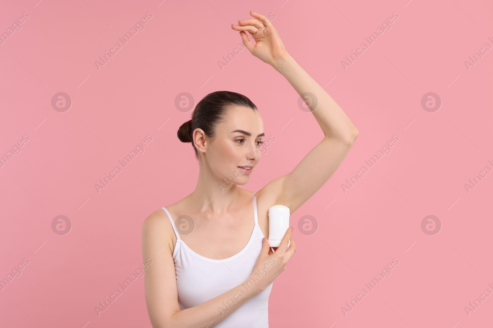 Photo of Beautiful woman applying deodorant on pink background