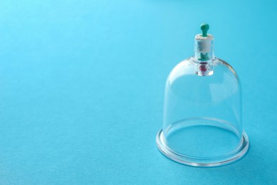 Photo of Plastic cup on light blue background, space for text. Cupping therapy