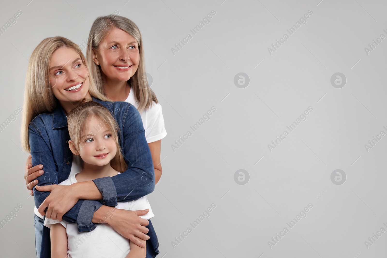 Photo of Three generations. Happy grandmother, her daughter and granddaughter on light gray background, space for text