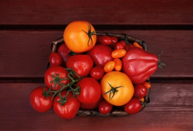 Photo of Basket with fresh tomatoes on wooden table, top view