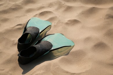 Pair of turquoise flippers on sand. Space for text