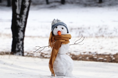Funny snowman with scarf and hat in winter forest