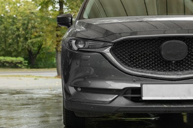 Photo of Black dirty car at outdoor carwash, closeup