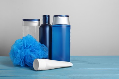 Photo of Different shower gel bottles with pouf on turquoise wooden table. Space for text