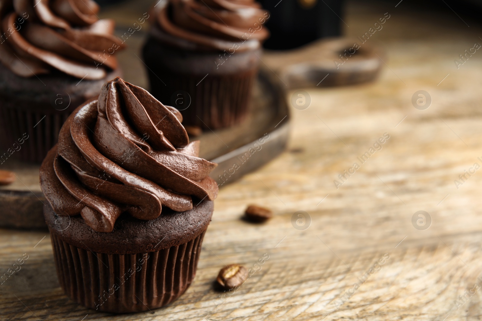 Photo of Delicious chocolate cupcake with cream on wooden table, closeup. Space for text