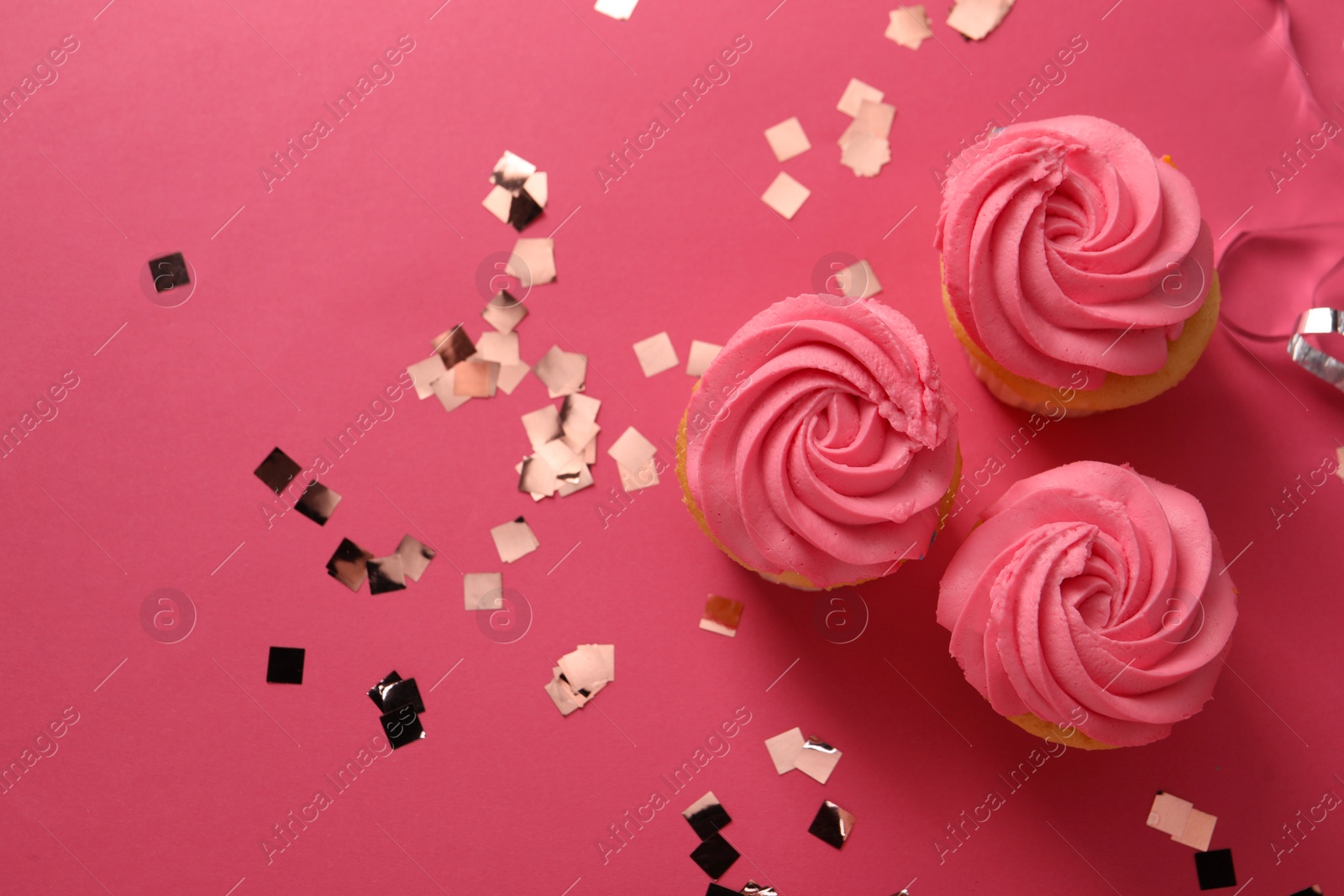 Photo of Delicious cupcakes with bright cream and confetti on pink background, flat lay. Space for text