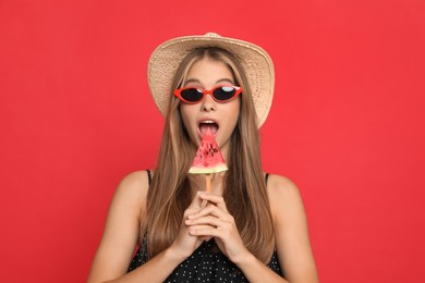 Beautiful girl with piece of watermelon on red background