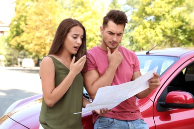 Photo of Young couple with map near car outdoors