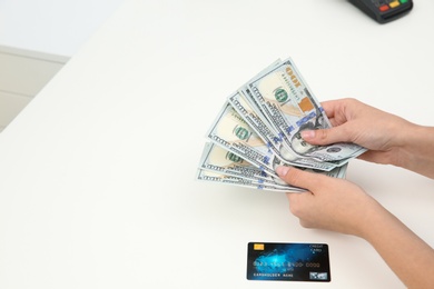 Photo of Woman with money and credit card at table, closeup