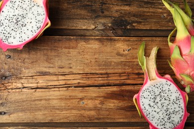 Photo of Delicious cut and whole dragon fruits (pitahaya) on wooden table, flat lay. Space for text