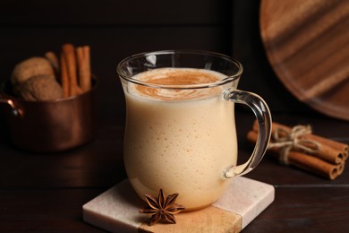 Photo of Delicious eggnog with spices on wooden table