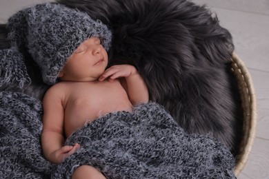 Photo of Adorable newborn baby lying in basket with faux fur