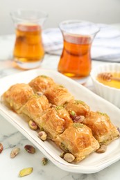 Photo of Delicious baklava with pistachios and scattered nuts on white marble table