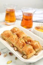 Delicious baklava with pistachios and scattered nuts on white marble table