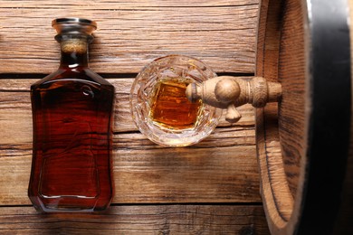 Photo of Glass and bottle of whiskey with wooden barrel on table, flat lay