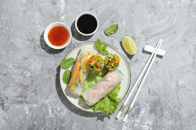 Tasty spring rolls served on grey textured table, flat lay. Space for text