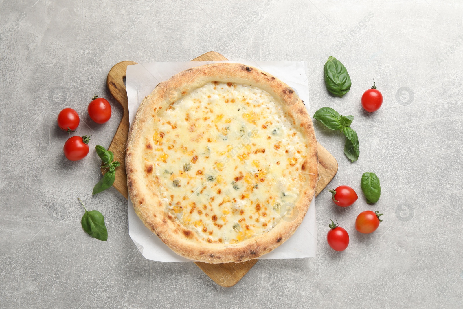 Photo of Delicious cheese pizza, basil and tomatoes on light grey table, flat lay