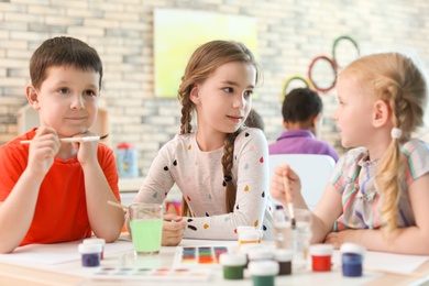 Photo of Cute little children painting at table indoors. Learning by playing