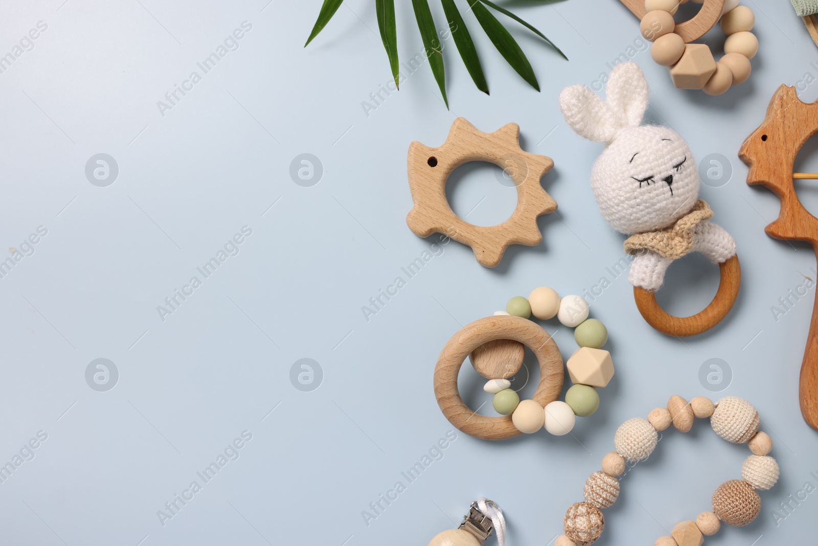Photo of Different baby accessories and palm leaf on light blue background, flat lay. Space for text
