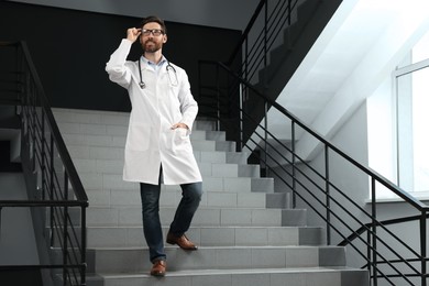 Doctor with stethoscope on stairs in hospital. Space for text
