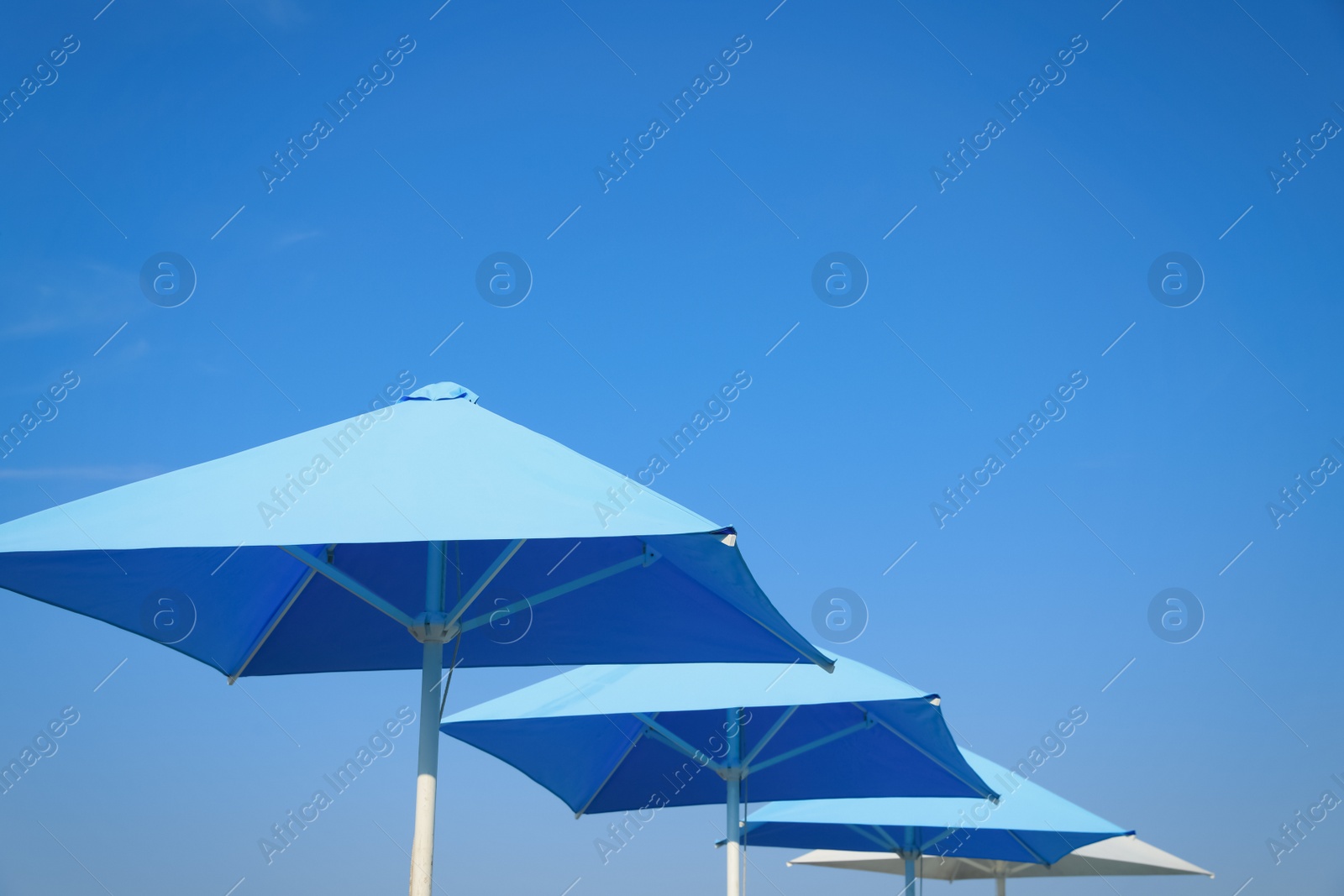 Photo of Bright beach umbrellas against blue sky on sunny day