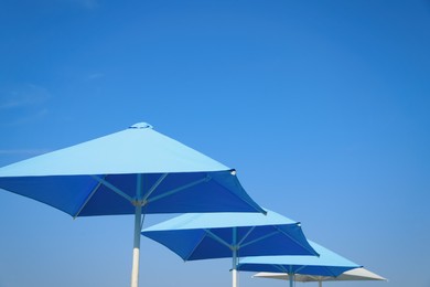 Photo of Bright beach umbrellas against blue sky on sunny day