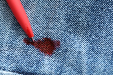 Pen and stain of red ink on jeans, top view. Space for text