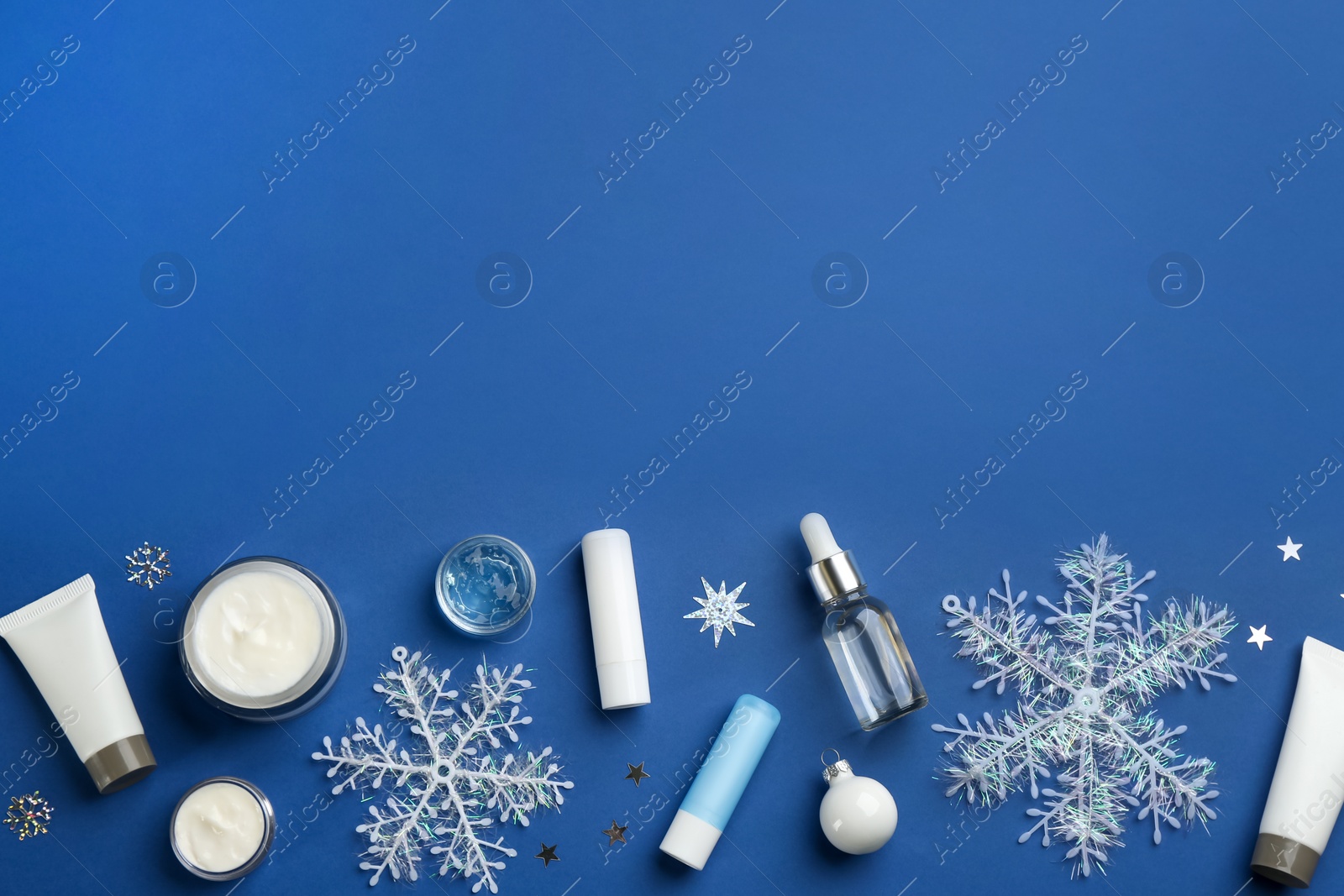 Photo of Flat lay composition with cosmetic products on blue background, space for text. Winter care