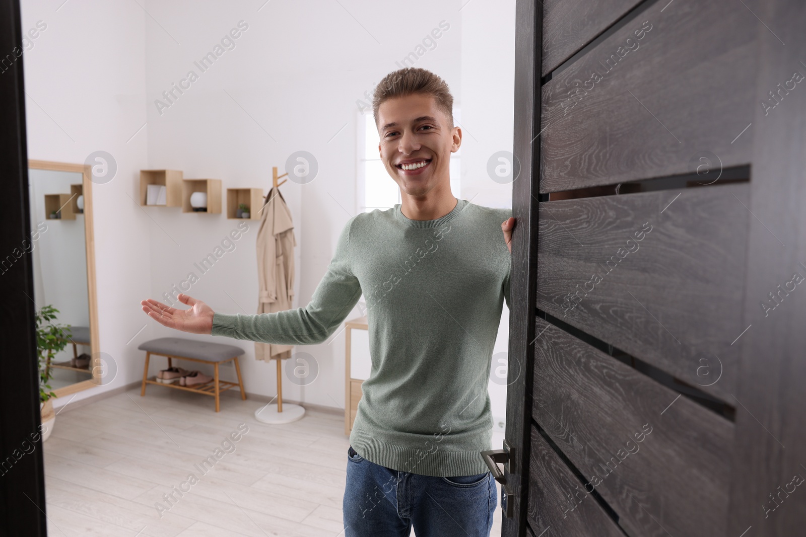 Photo of Happy man welcoming near door. Invitation to come indoors