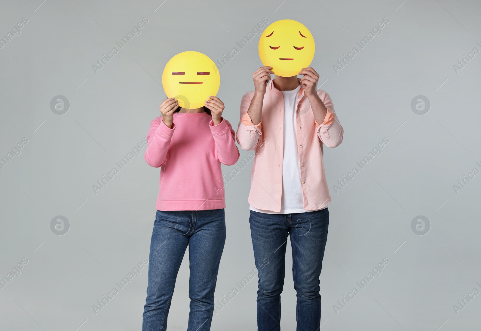 Photo of People covering faces with sad emoticons on grey background
