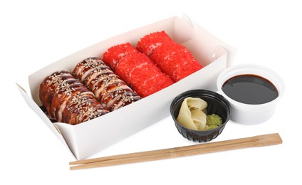 Photo of Food delivery. Paper box with different delicious sushi rolls near soy sauce, ginger, wasabi and chopsticks on white background