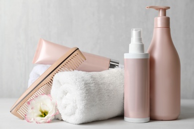 Different hair products, towel and comb on white wooden table