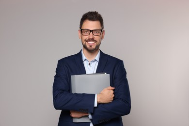 Photo of Happy teacher with glasses and stationery against beige background