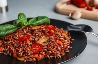 Photo of Plate of brown rice with vegetables on table, closeup