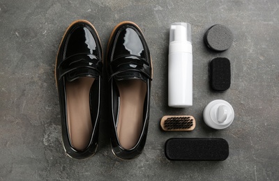 Flat lay composition with shoe care accessories and footwear on grey stone background